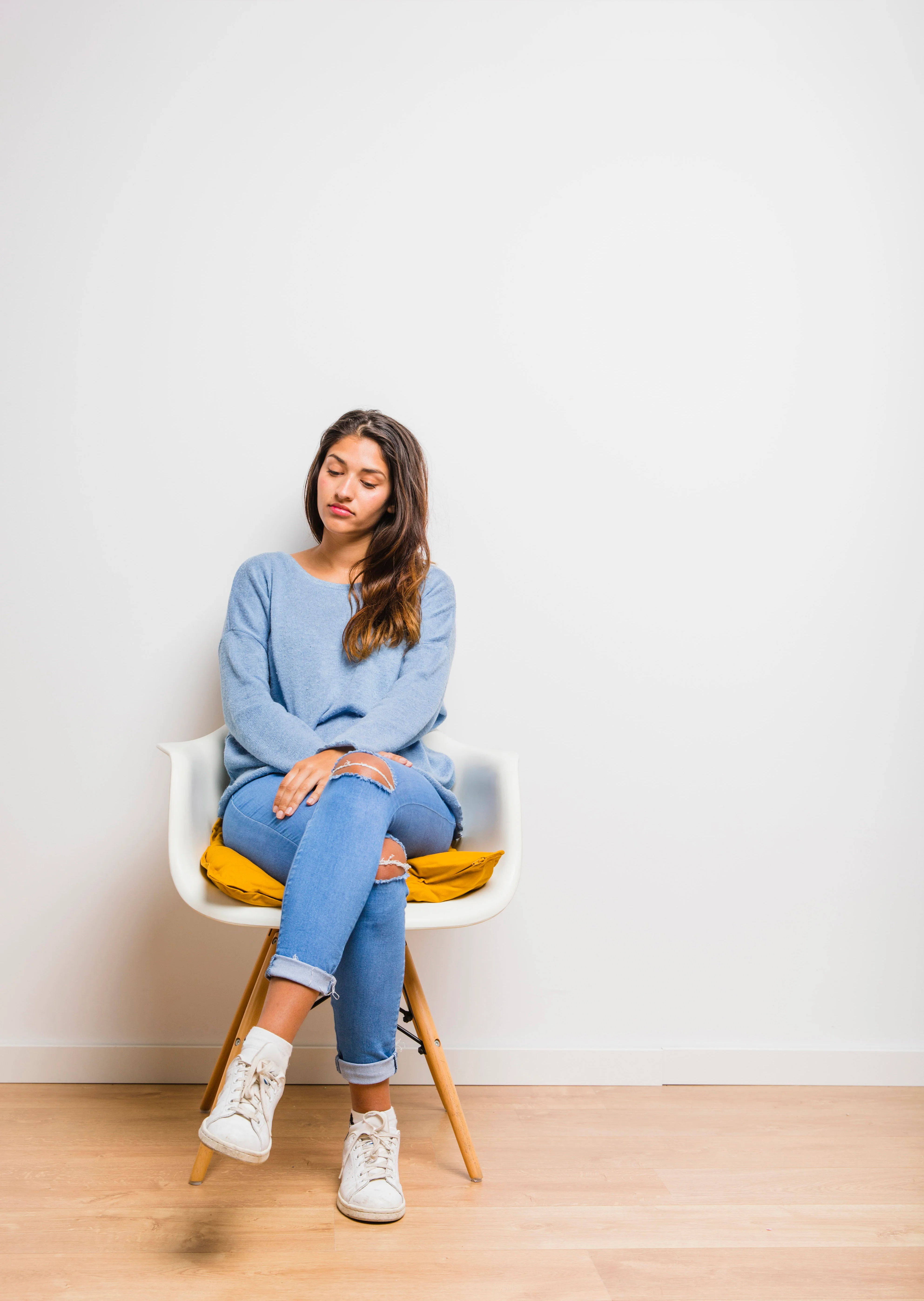 Brunette model feeling bored and sitting on a chair in an empty room